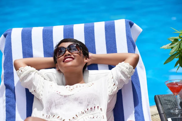 Mulher desfrutando de banhos de sol por piscina — Fotografia de Stock