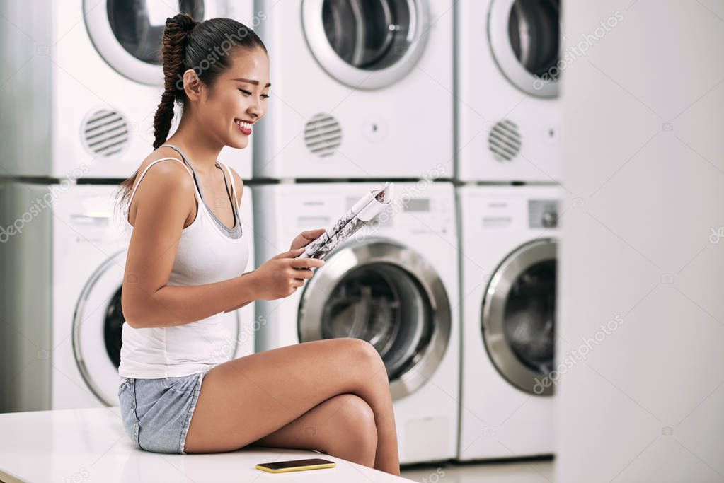 woman enjoying reading magazine in laundry room