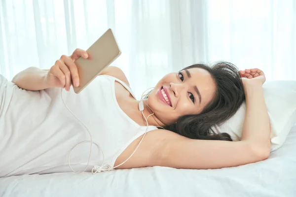 Mujer acostada en la cama con Smartphone —  Fotos de Stock