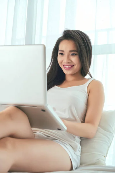 Mulher sentada na cama e trabalhando no laptop — Fotografia de Stock