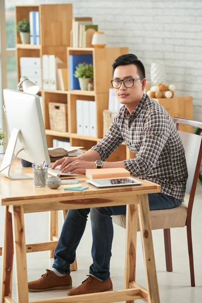 Mann arbeitet am Computer und blickt in Kamera — Stockfoto