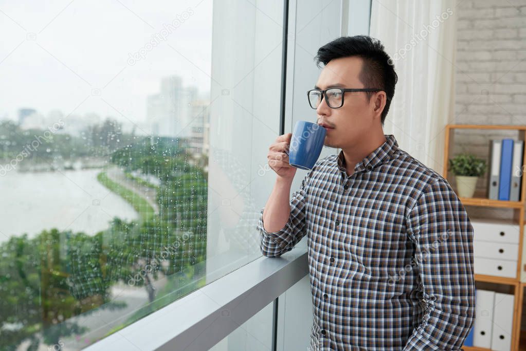 man enjoying cup of coffee on rainy day