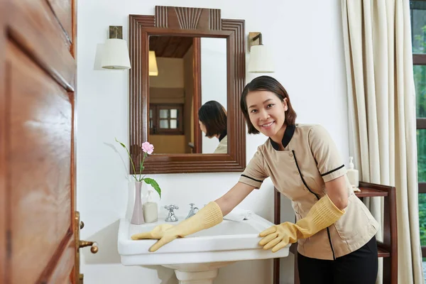 Zimmermädchen putzt Waschbecken im Badezimmer — Stockfoto