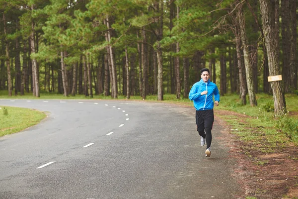Homem correndo ao longo da estrada — Fotografia de Stock