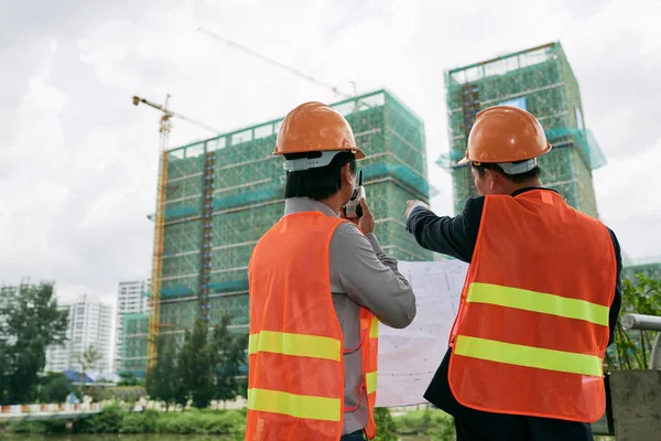 Empreiteiro e engenheiro examinando canteiro de obras — Fotografia de Stock