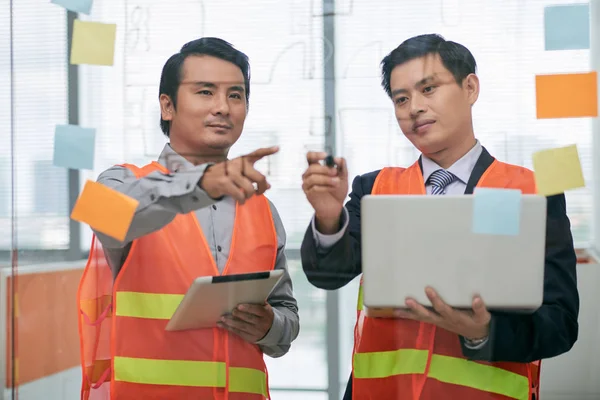 Ingenieros con computadora portátil y tableta apuntando al plano —  Fotos de Stock