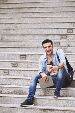 Adam merdivenlerinde oturmuş kahve ile