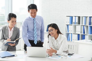 Dizüstü bilgisayar ekranındaki bilgileri tartışırken takım