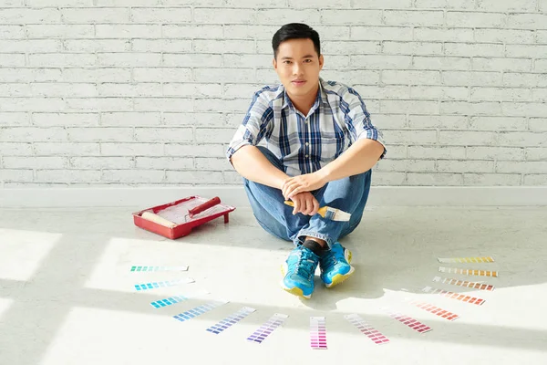 Muž sedí na podlaze s vzorkovací body barvy — Stock fotografie