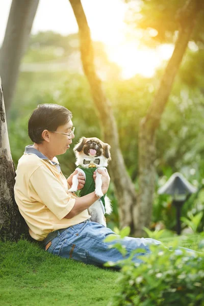 Homem sentado na grama e brincando com o cão — Fotografia de Stock