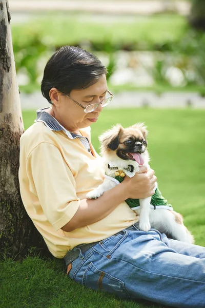 Homem sentado na grama e brincando com o cão — Fotografia de Stock