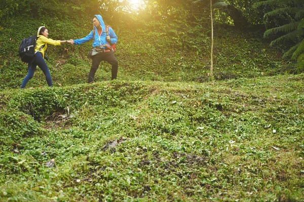 Viajante ajudando jovem mulher na floresta — Fotografia de Stock