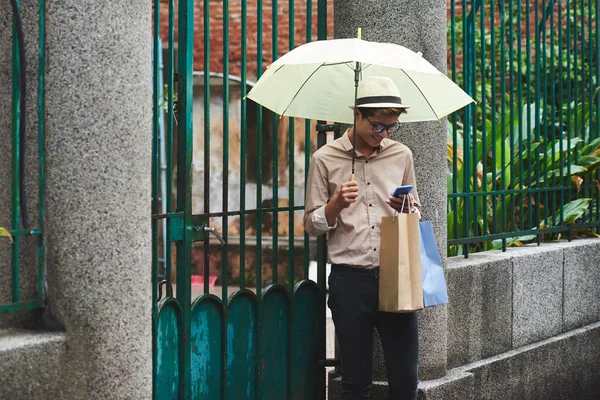 Muž s deštníkem kontrola smartphone — Stock fotografie