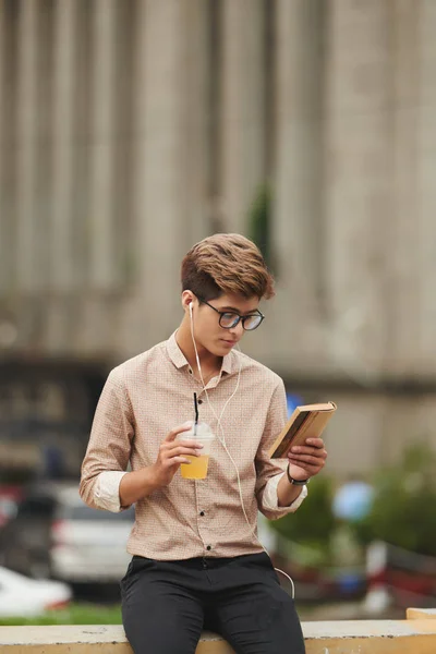 Man drinking juice and reading book