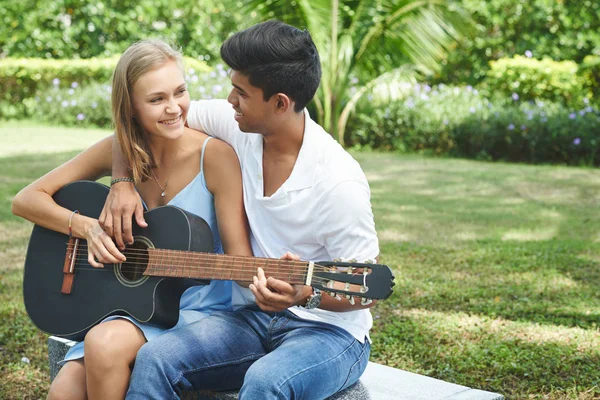 Multicultural couple playing on acoustic guitar — Stock Photo, Image