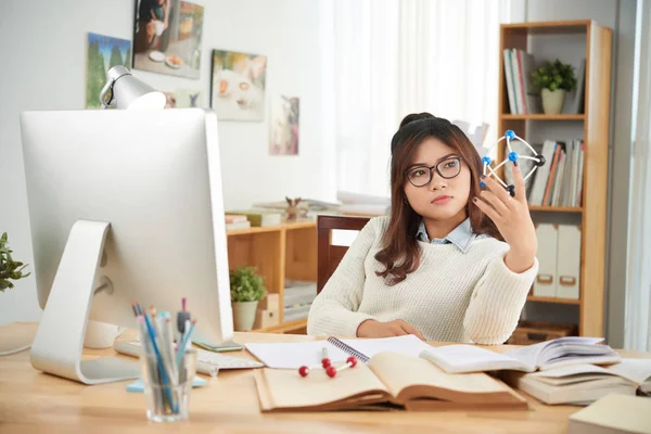 Student zittend aan tafel met model in de hand — Stockfoto