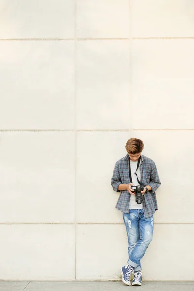 Young photographer standing at wall — Stock Photo, Image