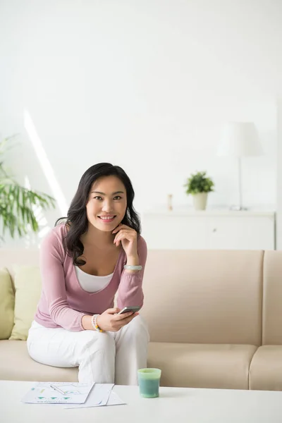 Wanita dengan smartphone duduk di sofa — Stok Foto