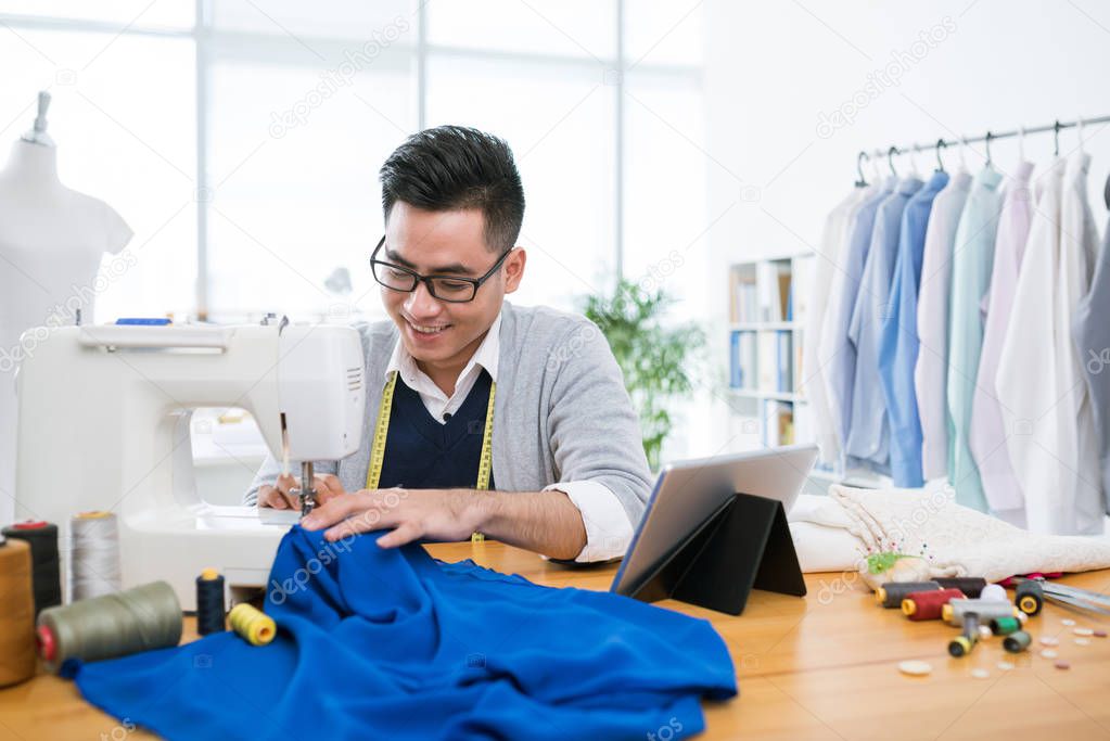 Young man sewing dress 