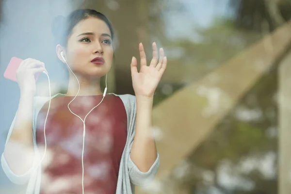 Mujer con auriculares de pie en la ventana —  Fotos de Stock