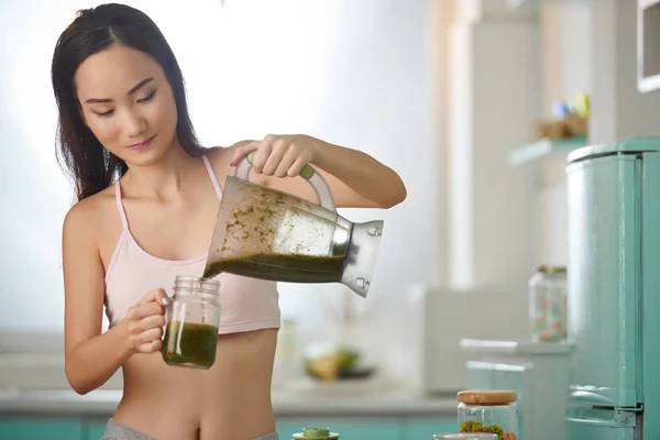 Frau schüttet Smoothie ins Glas — Stockfoto