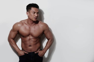 gömleksiz adam ayakta beyaz duvara karşı