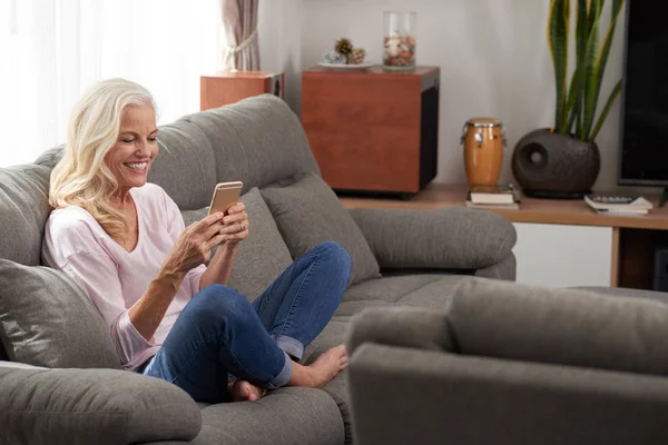 Жінка сидить на дивані і смс — стокове фото