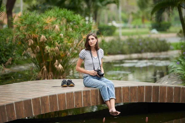Femme avec appareil photo numérique assis sur le pont — Photo
