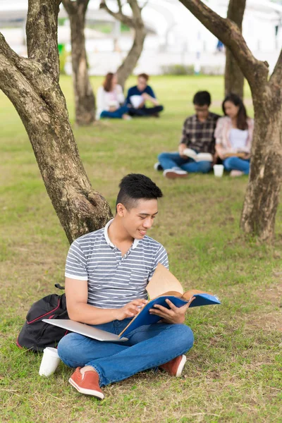 Student sitter och läser bok — Stockfoto