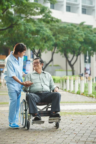Infermiere che cammina con paziente in sedia a rotelle — Foto Stock
