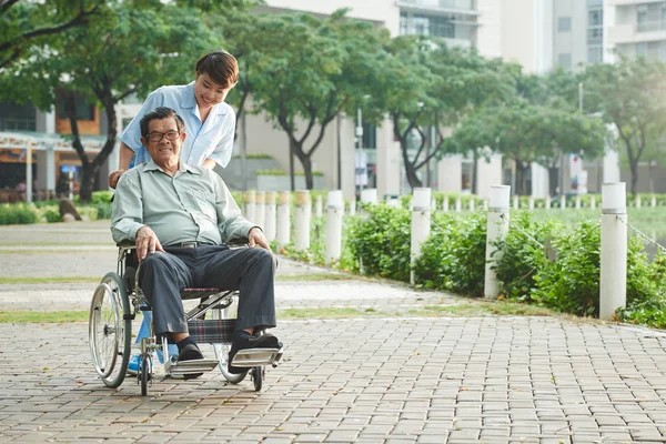 Медсестра, идущая с пациентом в инвалидном кресле — стоковое фото