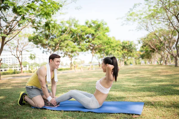 Man hjälper hans flickvän gör sit-ups — Stockfoto