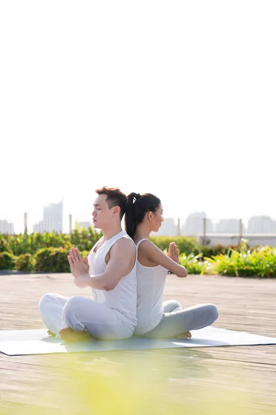 Ouple sitter rygg mot rygg när du mediterar — Stockfoto