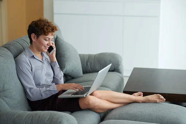 Frau sitzt auf Sofa und arbeitet am Computer — Stockfoto