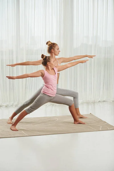 Chica y su madre disfrutando de la práctica de yoga —  Fotos de Stock