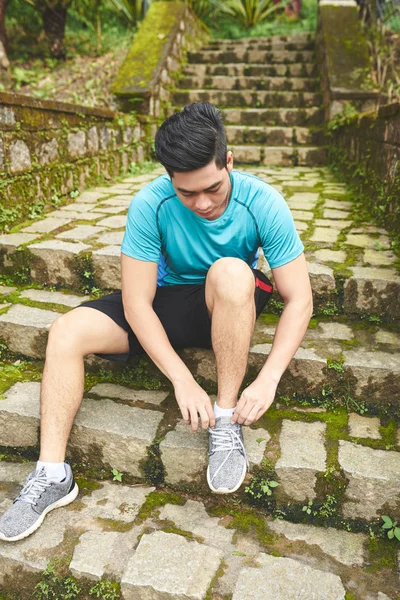 Man zittend op stappen en koppelverkoop sportschoenen — Stockfoto