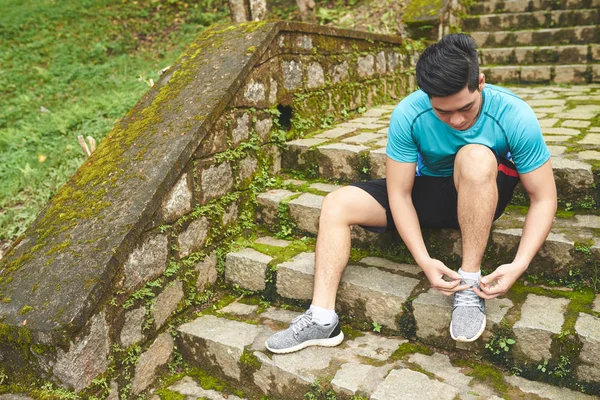 Człowiek siedzący na schodach i wiązanie sportshoes — Zdjęcie stockowe