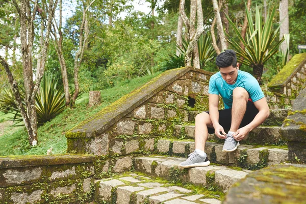 Homem sentado em passos e amarrando sapatos esportivos — Fotografia de Stock