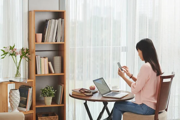 Wanita duduk dan menggunakan smartphone — Stok Foto