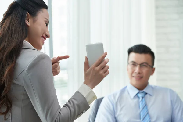 Lächelnde Geschäftsfrau zeigt auf Bildschirm des Smartphones — Stockfoto