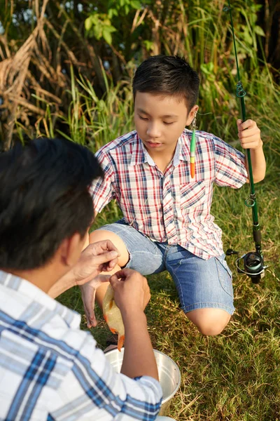 Man hjälper till att pojken med fiskeredskap — Stockfoto