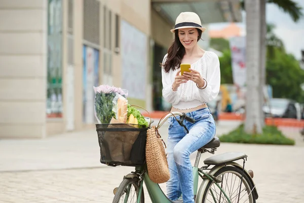 Mujer sosteniendo teléfono y bicicleta de montar —  Fotos de Stock