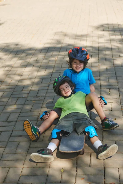 Meninos em capacete de proteção sentado no skate — Fotografia de Stock