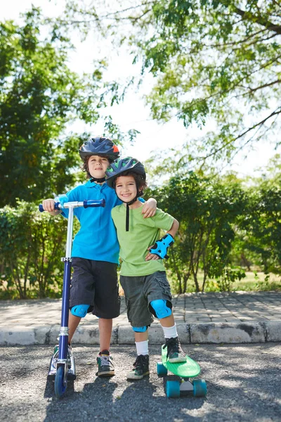 Bröderna står med sparkcykel och skateboard — Stockfoto