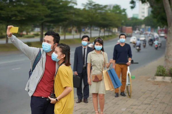 Couple in protective masks taking selfie — Stock Photo, Image