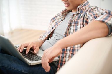 Serisi laptop izlerken kanepede oturan adam Resim kırpılmış