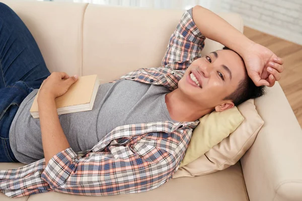 Asiática Sonriente Estudiante Con Libro Acostado Sofá Mirando Cámara — Foto de Stock