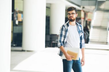 Açık havada duran dizüstü ve Not Defteri ile üniversite öğrencisi