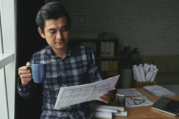专业的亚洲工程师喝咖啡 看蓝图 — 图库照片