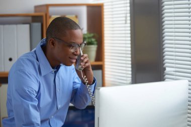 İstemci ile telefonda konuşurken gülümseyen siyah işadamı